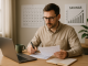 "Young adult planning retirement in their 30s with laptop and savings notes at home office."