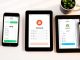 "Smartphone screens displaying YNAB, Monarch, and Rocket Money budget apps side by side on a modern desk setup"
